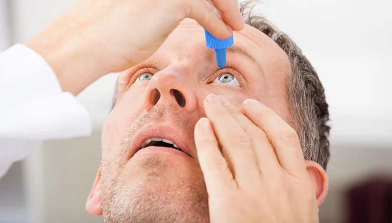 man with dry eye using eye drops