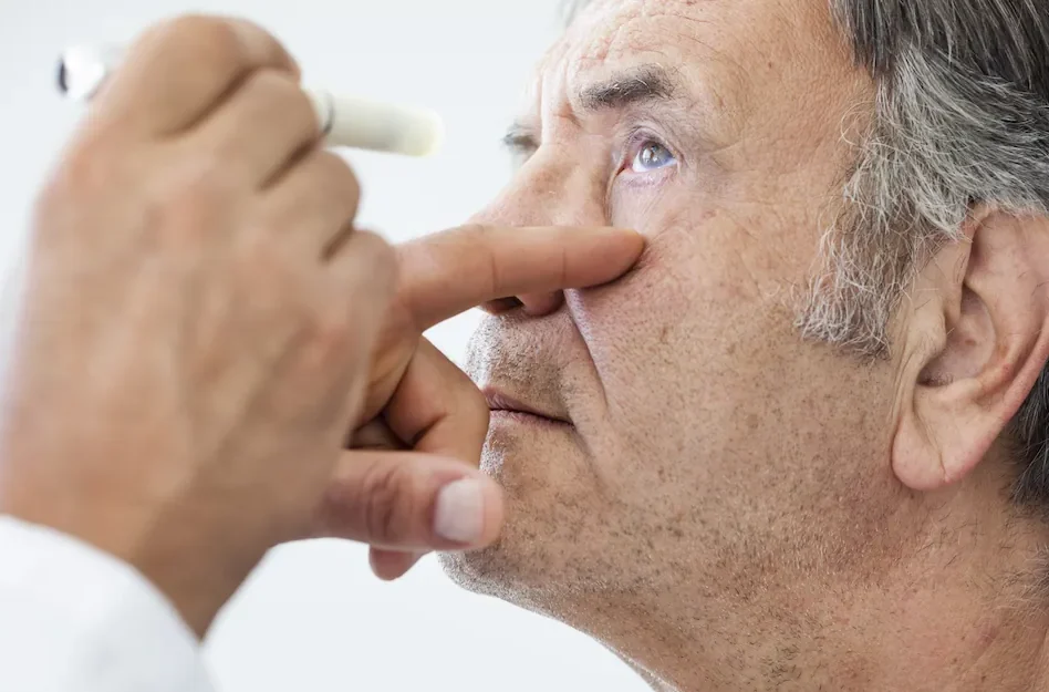 opthalmologist using a light to examine elderly man