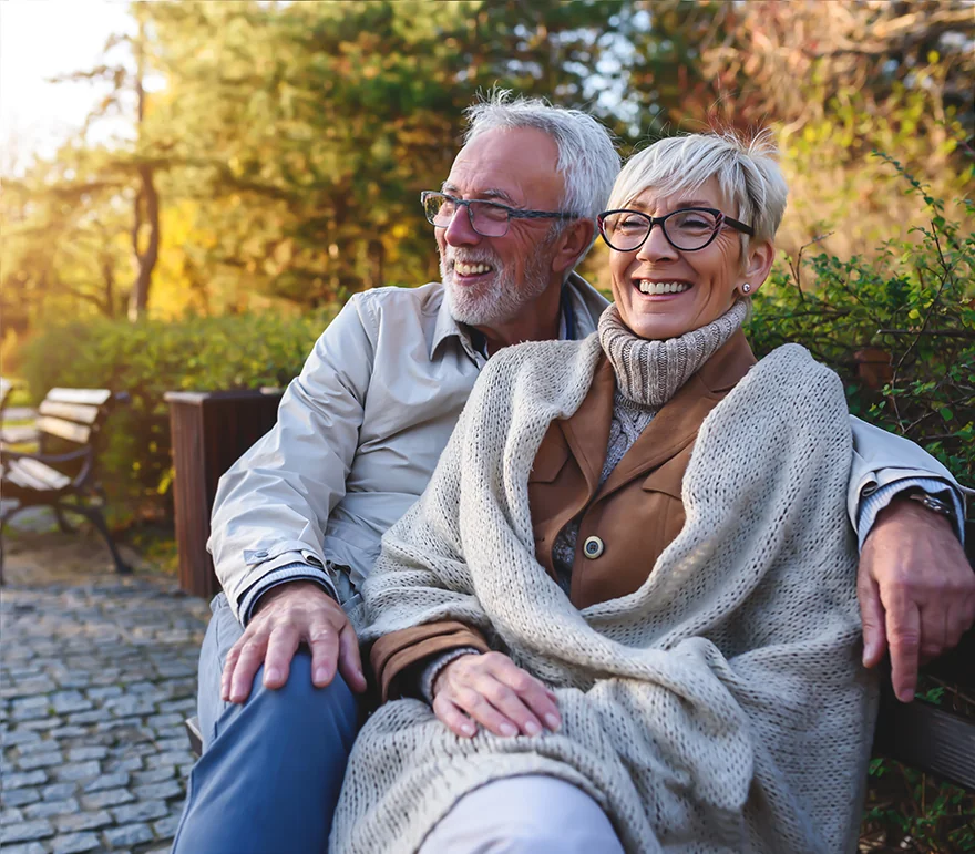 happy senior couple sitting on park bench