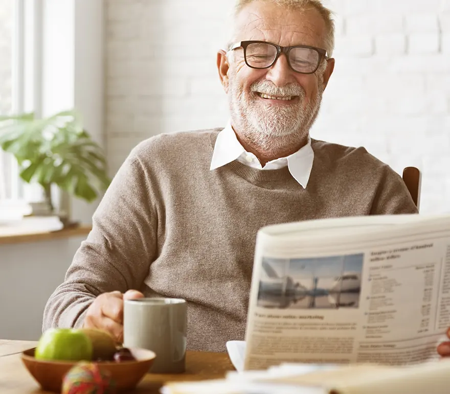 Senior man with glasses reading the newspaper