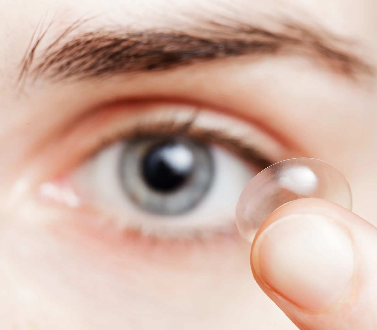 girl holding a contact lens in front of her eye
