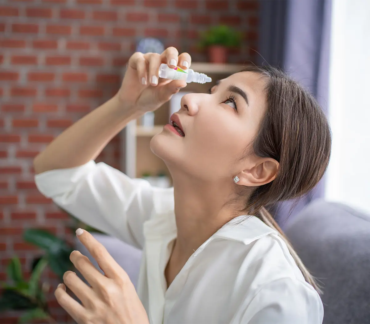 young asian woman using medical eye drops