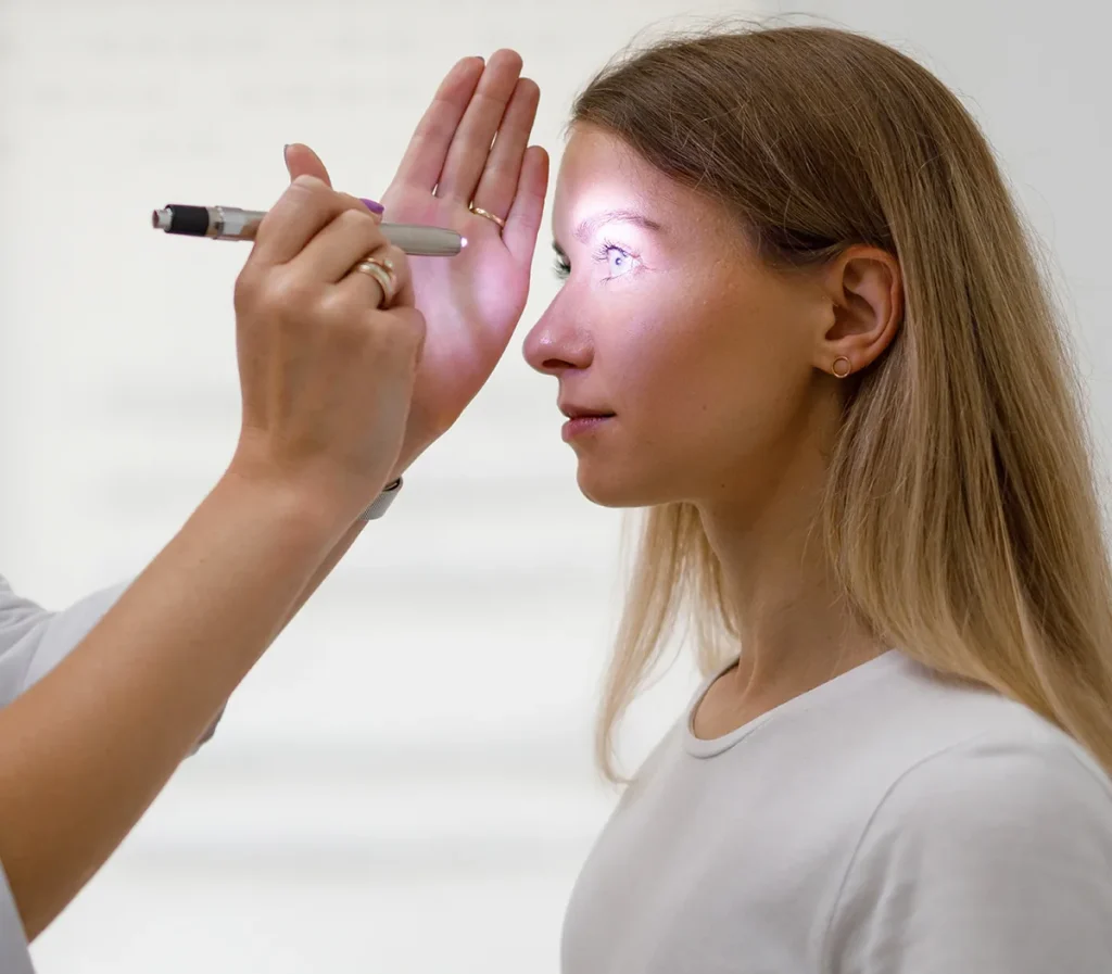 neuro-ophthalmologist examining patient's eye with flashlight