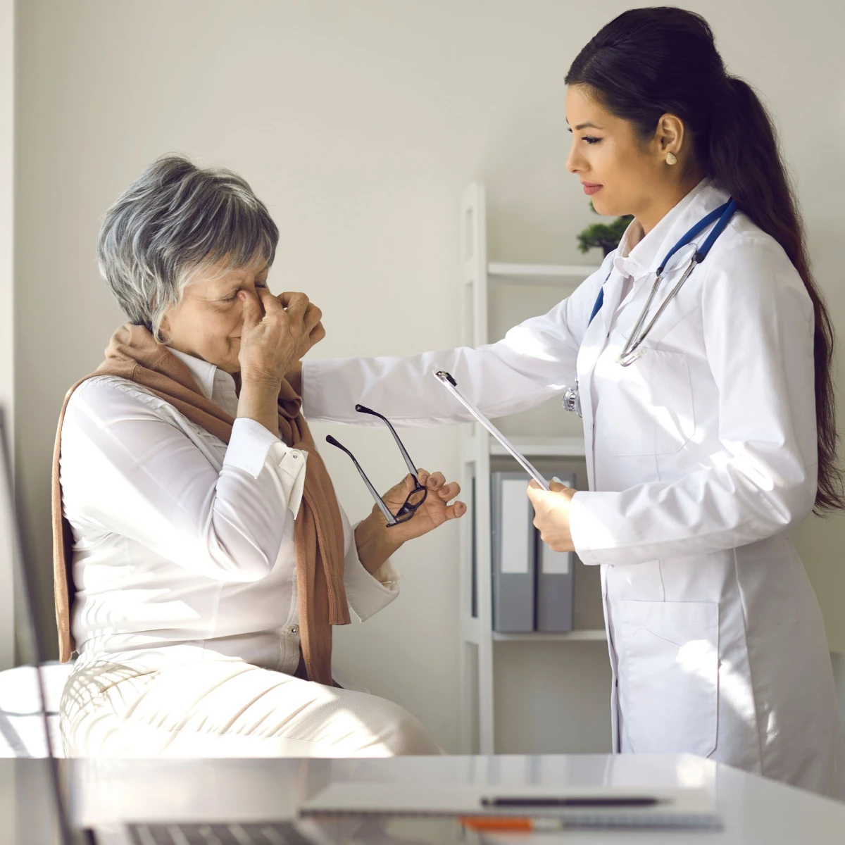senior woman explaining her symptoms to her eye doctor