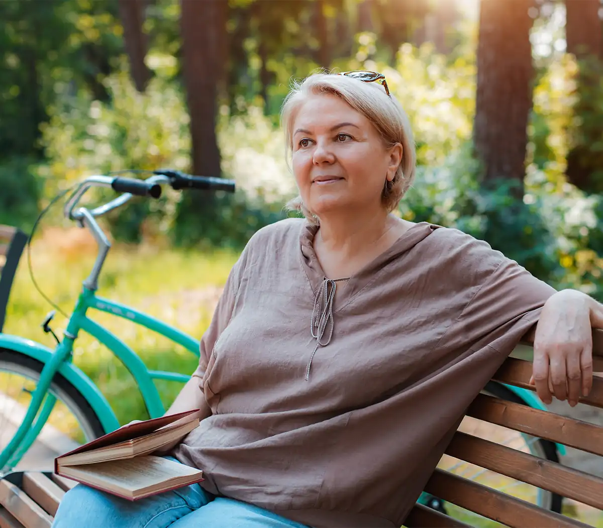 senior woman sitting on park bench with a book